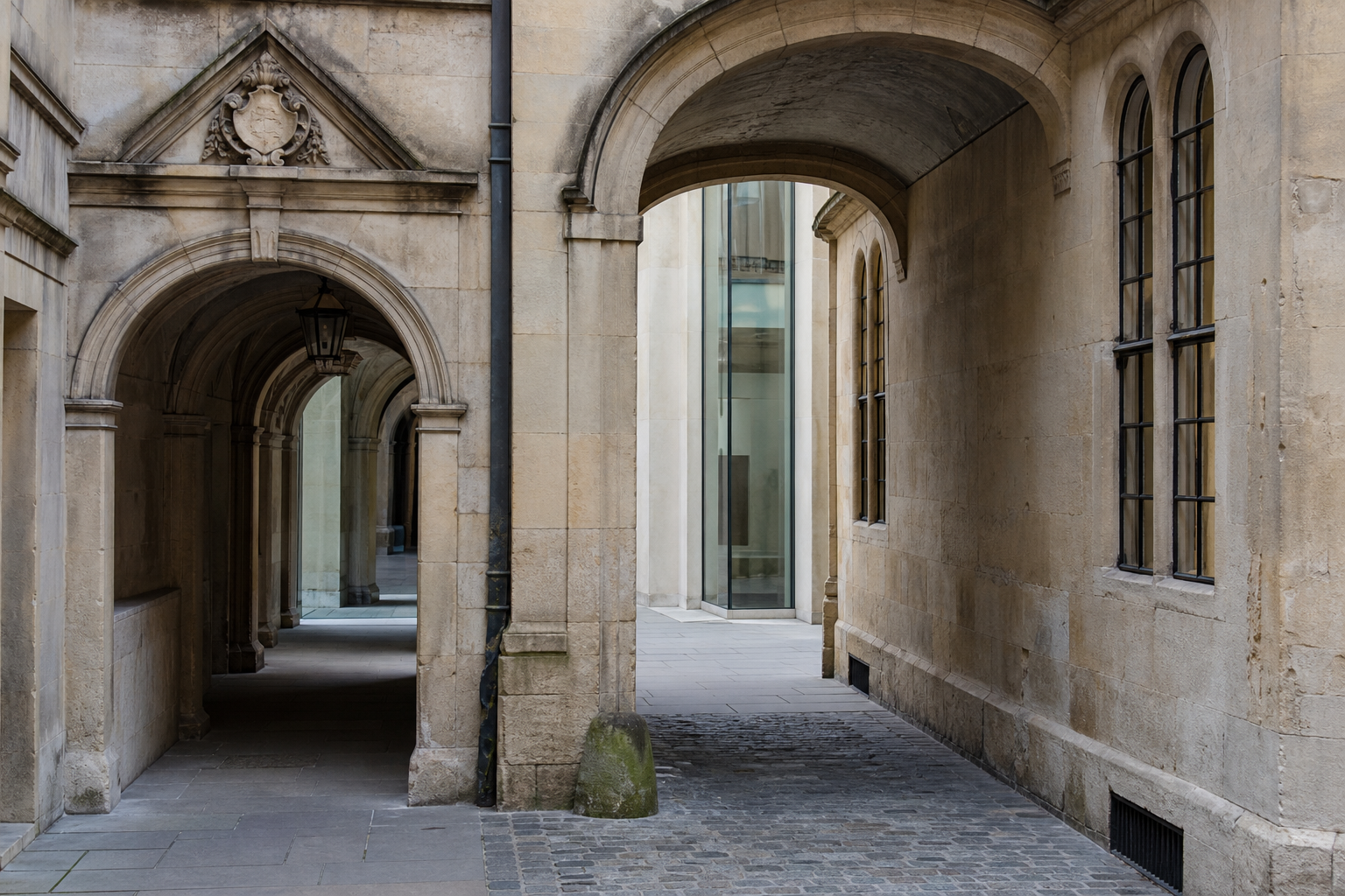 Historic university stone arches meeting a restrained contemporary glass intervention